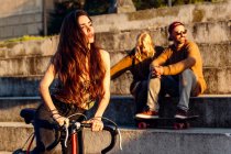Menina com bicicleta sobre casal sentado — Fotografia de Stock