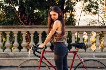 Девушка, стоящая на велосипеде — стоковое фото