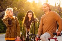 Two girls and man on bicycle in sunset light — Stock Photo