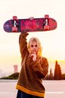 Girl holding skateboard over head — Stock Photo