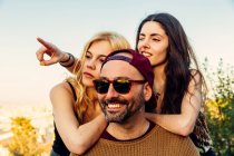 Two girls leaning on mans shoulder — Stock Photo