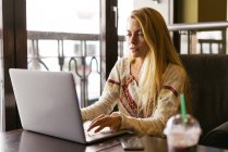 Усміхнена блондинка використовує ноутбук — стокове фото