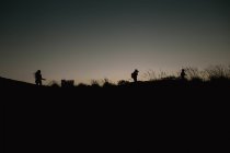 Three silhouettes on hill — Stock Photo