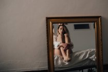Отражение женщины, обнимающей колени — стоковое фото