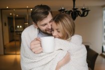 Couple hugging covered with plaid — Stock Photo