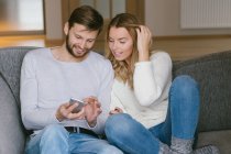 Пара переглядає смартфон на дивані — стокове фото