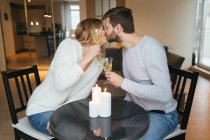 Pair kissing and holding wine glasses — Stock Photo