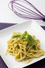 Spaghetti with pesto sauce on square plate — Stock Photo
