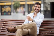 Junger Mann sitzt auf Holzbank — Stockfoto