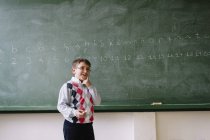Kleines Kind steht im Klassenzimmer an der Tafel — Stockfoto