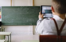 Boy taking shots of blackboard — Stock Photo