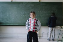 Little kid standing at blackboard in classroom — Stock Photo