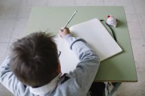 Маленький мальчик пишет для копирования книги — стоковое фото