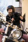Motociclista barbudo colocando no capacete — Fotografia de Stock