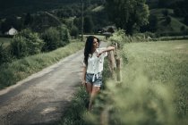 Jolie femme à la clôture rurale — Photo de stock