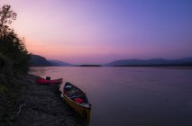 Kayaks on shore of lake in sunset — Stock Photo