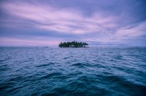 Island in ocean under colorful sky — Stock Photo