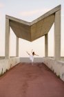 Rear view of of ballerina in pose under urban concrete canopy — Stock Photo