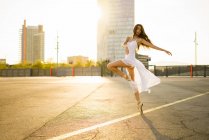 Sensual ballerina dancing on sunlit asphalt square — Stock Photo