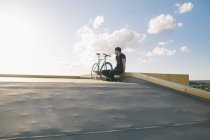 Menino de preto sentado perto da bicicleta — Fotografia de Stock