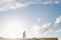 Boy ridding bike over sky — Stock Photo