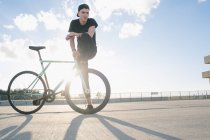 Cyclist with leg on bikes wheel — Stock Photo