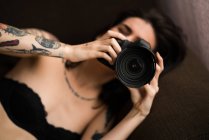 Pretty woman lying and holding camera — Stock Photo