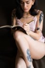 Mulher tatuada escrevendo no caderno — Fotografia de Stock