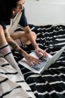 Feminino digitando no laptop sentado na cama — Fotografia de Stock