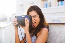 Donna con la lingua fuori tenendo macchina fotografica — Foto stock