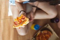 Young woman holding slice of pizza — Stock Photo