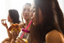 Mulheres comendo pizza e bebendo um suco — Fotografia de Stock