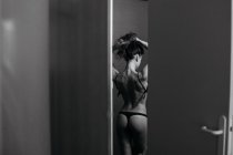Visão traseira da mulher sensual em lingerie preta despir . — Fotografia de Stock