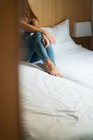 Cultivo piernas femeninas en la cama en casa - foto de stock