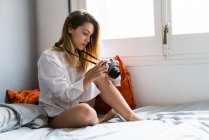 Mädchen stellt Kamera auf das Bett — Stockfoto