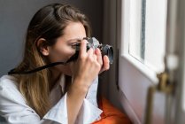 Woman with camera shooting window — Stock Photo