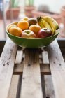 Свіжі фрукти в мисці на дерев'яній поверхні — стокове фото