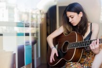 Молода дівчина з гітарою через вікно — стокове фото