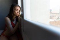 Menina em lingerie olhando para fora da janela — Fotografia de Stock