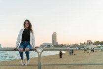 Смеющаяся девушка на заборе на пляже — стоковое фото