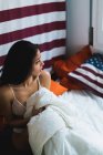 Женщина сидит на кровати, покрытой одеялом — стоковое фото
