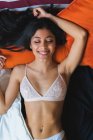 Feminino vestindo sutiã deitado na cama — Fotografia de Stock