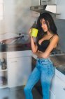 Feminino em pé na cozinha com caneca verde — Fotografia de Stock