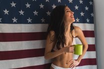 Feminino com copo no fundo da bandeira americana — Fotografia de Stock