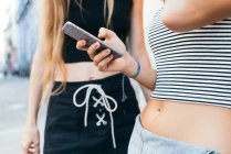Дві невпізнавані сексуальні дівчата використовують смартфон — стокове фото