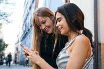 Дві молоді подружки використовують смартфон — стокове фото
