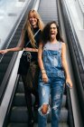 Fröhliche Freundinnen haben Spaß auf Rolltreppe — Stockfoto