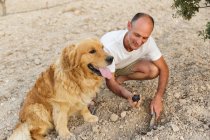 Люди с золотой собакой-ретривером и лопатой в руке копают яму — стоковое фото