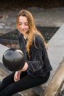 Giovane donna in possesso di palloncino nero . — Foto stock