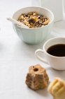 Tigela branca com granola e xícara de café na mesa branca — Fotografia de Stock